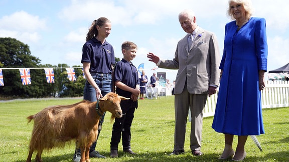König Charles III. und Königin Camilla (r) besichtigen während ihres zweitägigen Besuchs auf den Kanalinseln die seltenen Goldenen Guernsey-Ziegen bei einem Besuch in Les Cotils in L'Hyvreuse.