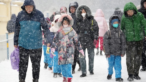 Eltern bringen ihre Kinder bei Schneefall zur Schule