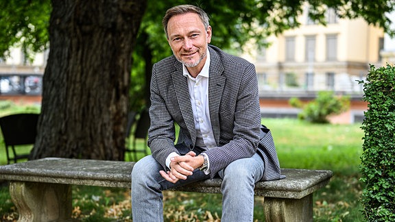 Finanzminister Christian Lindner (FDP), 2023 während eines Interviews auf einer Parkbank sitzend 