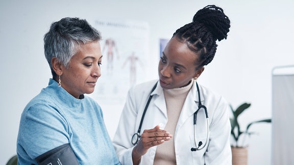Eine Ärztin und eine ältere Patientin beim Blutdruckmessen.