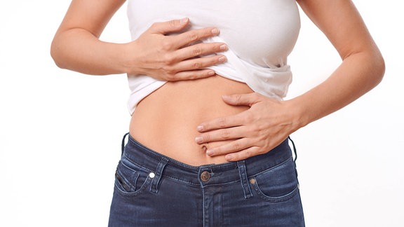 Junge Frau hält sich den Bauch.