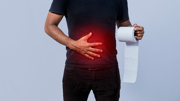 Mensch mit einer Hand auf dem Bauch hält Toilettenpapier.