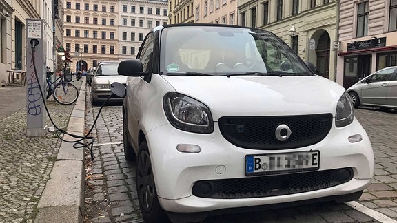 Ein Elektroauto wird in einem Wohngebiet an einer öffentlichen Ladesäule aufgeladen