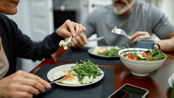 Ehepaar isst Spiegeleier und Salat zum Frühstück zu Hause 