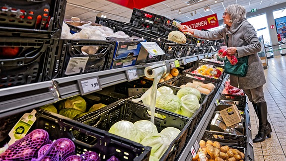 Eine Frau beim Einkauf in der Gemüseabteilung eines Supermarktes.