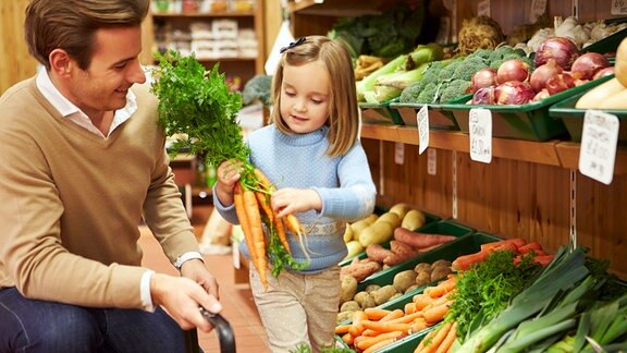 Vater und Tochter am Gemüseregal im Supermarkt
