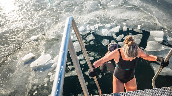 Zwei Winterbader schwimmen mit Eisbrocken an einem sonnigen Tag