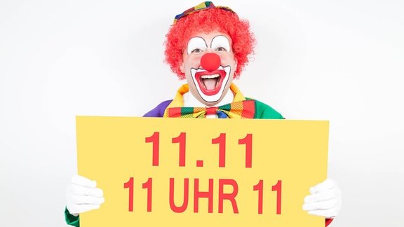 Clown hält Schild mit Aufschrift '11.11. 11 Uhr 11'