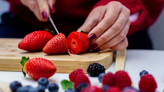 Eine Frau schneidet Erdbeeren.