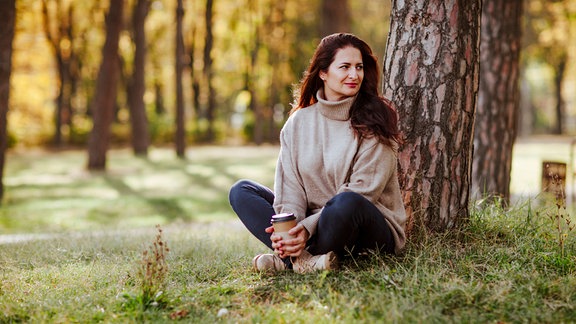 Eine Frau sitzt an einem Baum