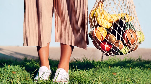 Frau mit einen mit Obst gefüllten Einkaufsnetz
