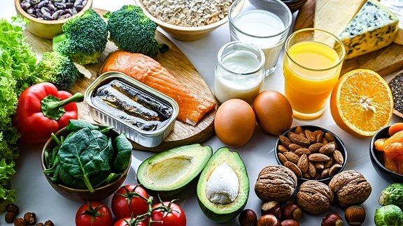 Obst, Gemüse, Fisch, Eier und Orangensaft auf einem Tisch.