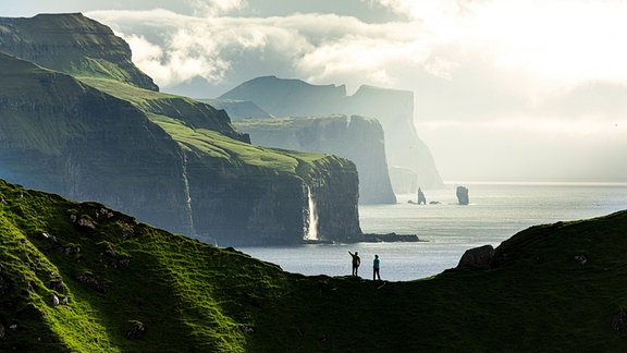 Silhouette von Wanderern, die Klippen bewundern, die auf einem Bergrücken über dem Meer stehen, Insel Kalsoy, Färöer Inseln