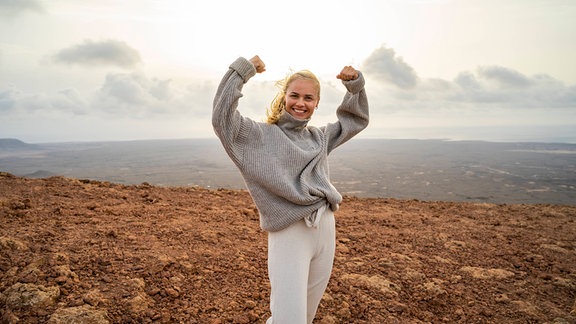 Lächelnde Frau mit Siegerpose in der Natur