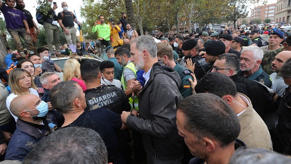 Spaniens König Felipe VI. (Mitte) verlässt den Schauplatz, nachdem eine Menge wütender Überlebender der Überschwemmungen in Spanien den König und Regierungsbeamte bei ihrem ersten Besuch in einer der am stärksten betroffenen Städte mit Schlamm beworfen und beschimpft hatten.