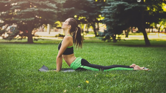 Fitness, Frau trainiert Yoga in Kobra-Pose im Freien im Park