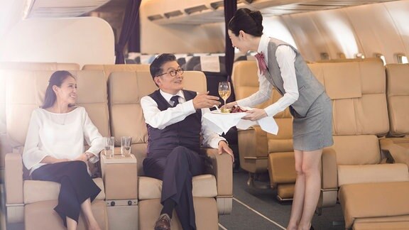 Eine Flugbegleiterin serviert Essen an Passagiere