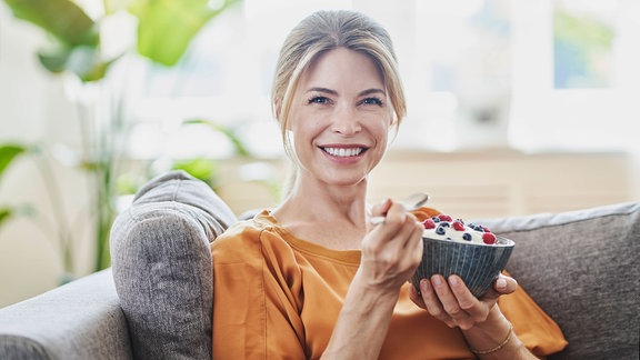 Frau isst Müsli und lächelt