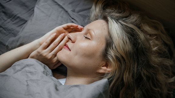 Ein Frau liegt in einem Bett und schläft.