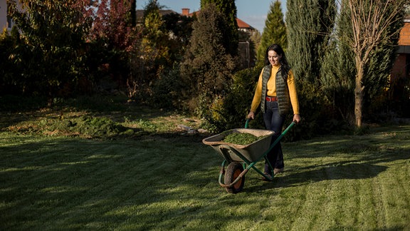 Frau mit Schubkarre in einem Garten