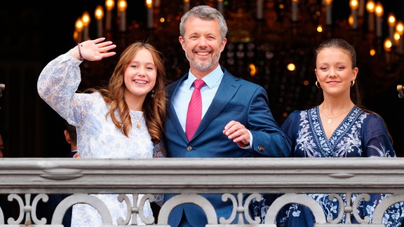Dänemarks König Frederik X., der seinen 56. Geburtstag feiert, winkt vom Balkon mit seinen Töchtern Prinzessin Josephine (l) und Prinzessin Isabella im Palast von Frederik VIII., Schloss Amalienborg in Kopenhagen