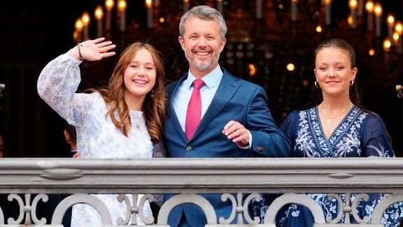 Dänemarks König Frederik X., der seinen 56. Geburtstag feiert, winkt vom Balkon mit seinen Töchtern Prinzessin Josephine (l) und Prinzessin Isabella im Palast von Frederik VIII., Schloss Amalienborg in Kopenhagen