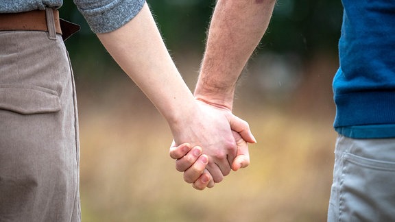 Eine Frau und ein Mann halten sich an den Händen.
