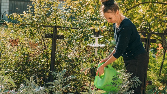 Frau mit Gießkanne im Garten.
