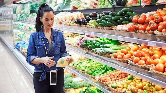 Junge Frau am Gemüsestand im Supermarkt