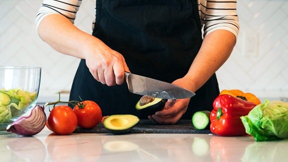 Frau schneidet Gemüse in der Küche