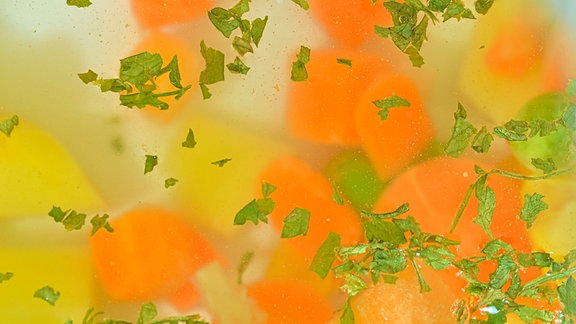 Gemüsestückchen in kochendem Wasser mit Kräutern.