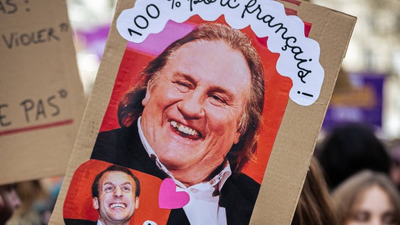Eine Frau hält während der Demonstration zum Internationalen Frauentag ein Plakat mit dem Bild von Gerard Depardieu mit der Aufschrift „100 % französisches Schwein“.