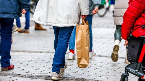 Menschen mit Einkaufstüten laufen durch eine Innenstadt.