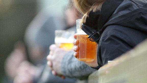 Zwei Zuschauer halten Plastikbecher mit Bier in der Hand.