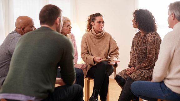 Menschen sitzen in einer Gruppentherapie im Kreis