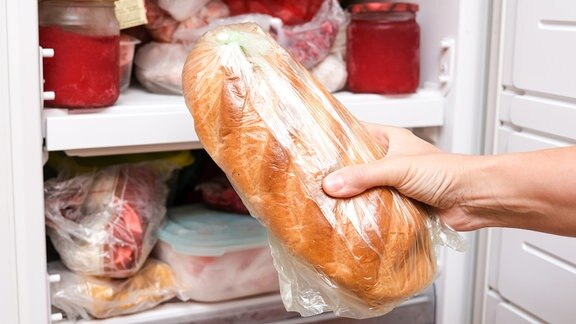 Eine Hand nimmt ein Brot aus der Tiefkühltruhe.