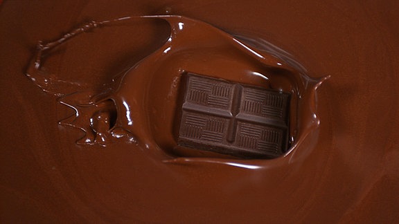 Schwarze Schokoladentafel, die in Vollmilchschokolade fällt.