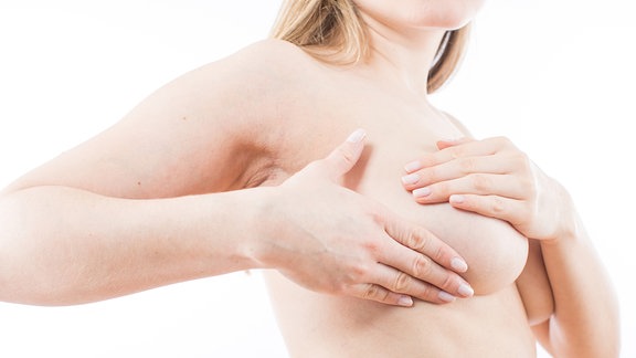 Eine junge Frau tastet 2017 ihre Brust ab