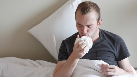 Mann mit Grippe im Bett