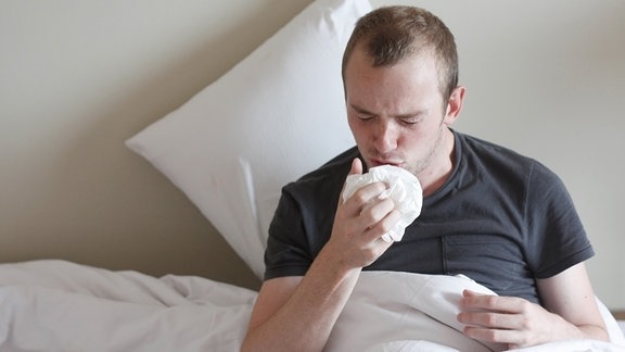 Mann mit Husten im Bett