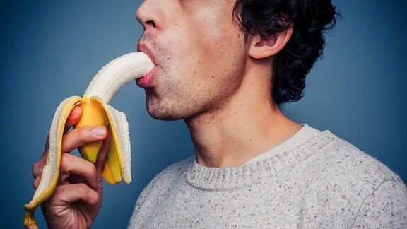 Mann steckt sich eine Banane in den Mund