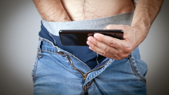 Ein Mann sieht sich auf seinem Smartphone Inhalte für Erwachsene an.