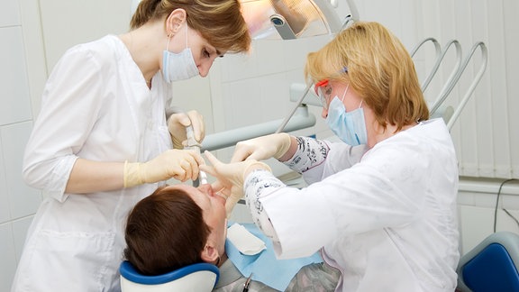 Eine Zahnärztin behandelt einen Patienten