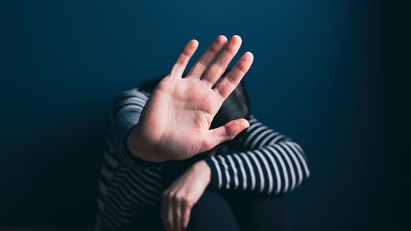 Frau hält ihre Hand abwehren vor Gesicht