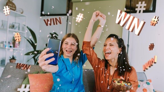 Zwei Influencerinnen bewerben föhlich per Smartphone ein Gewinnspiel.