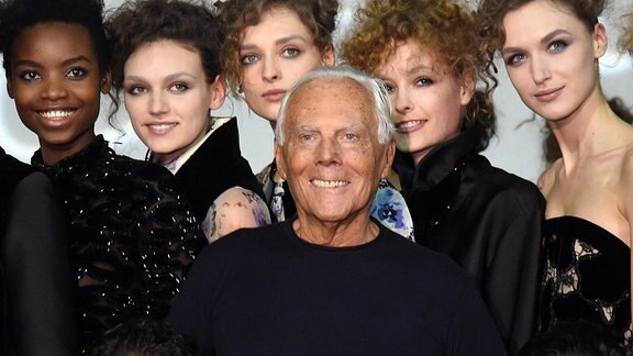 Giorgio Armani steht vor einigen Models.