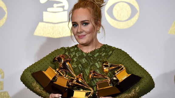 Sängerin Adele posiert mit ihren Auszeichnungen in den Armen.