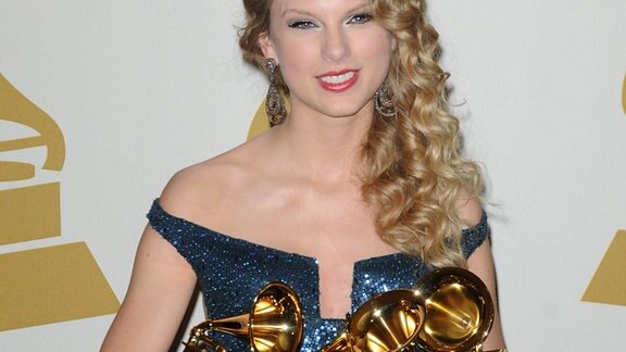 Taylor Swift posiert mit ihren Auszeichnungen in den Armen