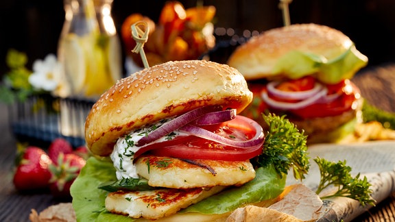 Vegetarischer Burger mit gegrilltem Halloumi-Käse, frischem Salat, Tomaten, Gurken und Zwiebeln, dazu Joghurt-Minz-Sauce.