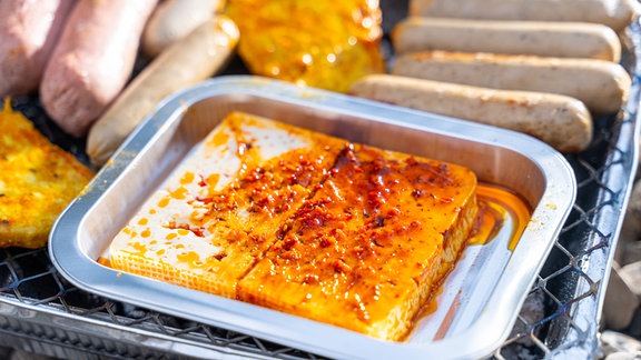 Ein Grillkäse in einer Aluminium-Schale auf einem Grill.